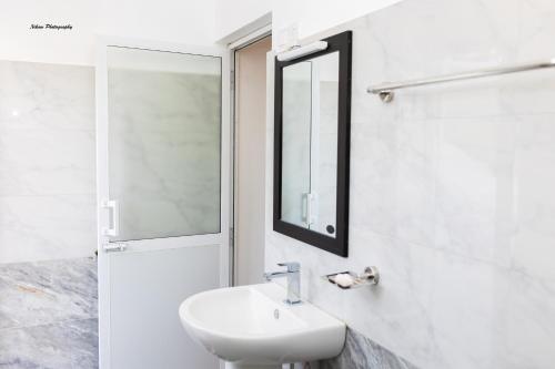 a white bathroom with a sink and a mirror at The Fort House - Matara in Matara
