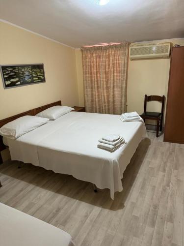 a bedroom with two beds and a chair and a window at Hotel Tania in Casa Giosafat