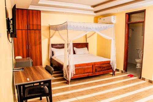 a bedroom with a canopy bed and a desk at Armaflex hotel SMC LTD in Lira
