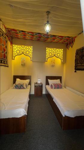 two beds in a room with yellow walls at Mahalla Old City Samarkand in Samarkand