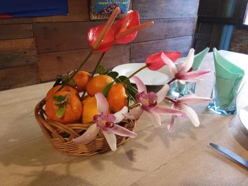 a basket of oranges and flowers on a table at Gite Chez Théo in Saint-Paul