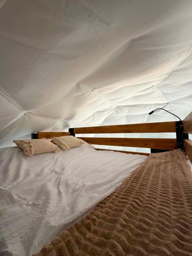 a bed in a tent with two pillows on it at Glamping Bieszczadzki Amor in Zawóz