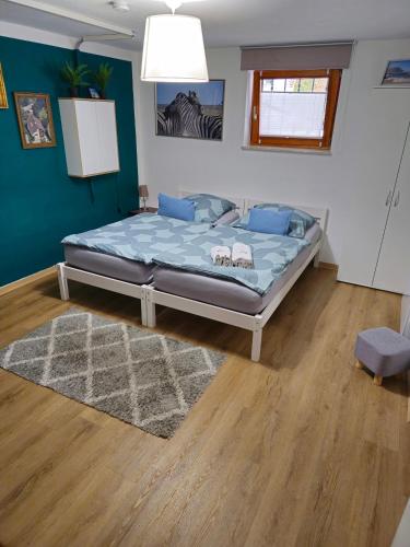 a bedroom with a bed with blue sheets and a rug at Ruhige, modern eingerichtete 2 Zimmer Wohnung im Untergeschoss eines Zweifamilienhauses in Hildrizhausen