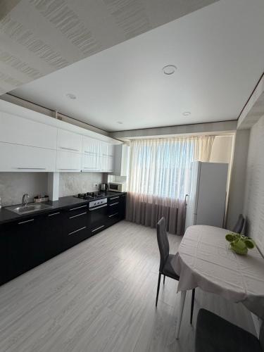 a kitchen with a table and a kitchen with white cabinets at Apartament in Chişinău