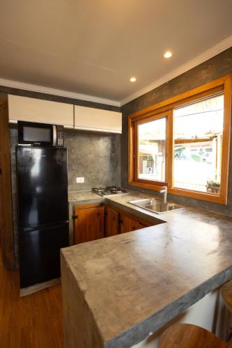 a kitchen with a black refrigerator and a sink at Maré Alta - Guest House in Ilha do Mel