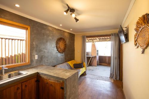 a kitchen with a sink and a living room at Maré Alta - Guest House in Ilha do Mel