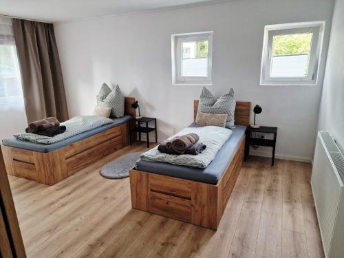two beds in a room with wooden floors and windows at Weitblick am Rammenfeld in Schönecken