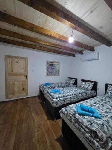 two beds in a room with wooden floors and a door at Adventure Tara in Foča