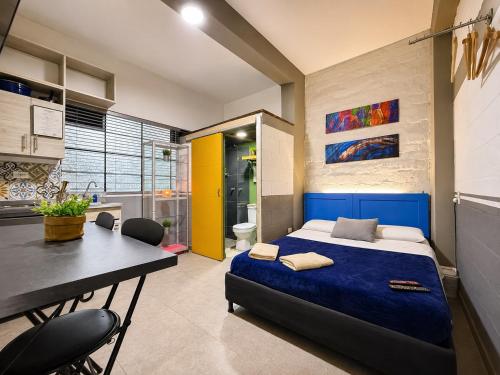 a bedroom with a blue bed and a desk and a bathroom at La Gruta Coliving in Medellín