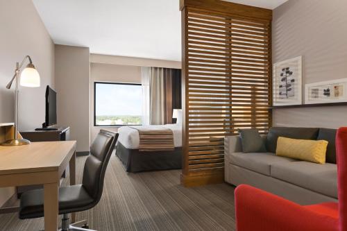 a hotel room with a bed and a couch and a desk at Country Inn & Suites by Radisson, Smithfield-Selma, NC in Smithfield