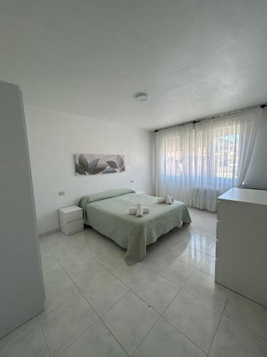 a white bedroom with a bed and a window at Apartamento céntrico Prado Blanco in Finisterre