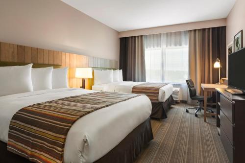 a hotel room with two beds and a desk at Country Inn & Suites by Radisson, Smithfield-Selma, NC in Smithfield