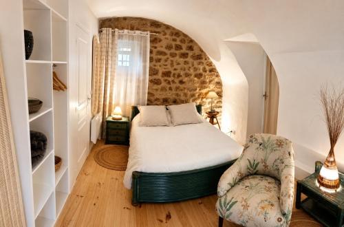 a bedroom with a bed and a chair at "La Voûte de Pierre" Gîte indépendant in Saint-Cyr