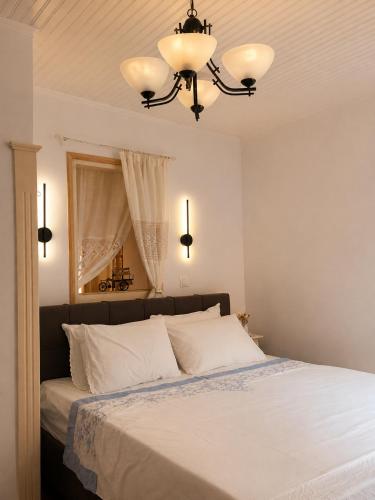 a bedroom with a bed with white sheets and a chandelier at Lichno Spirit in Vourliótai