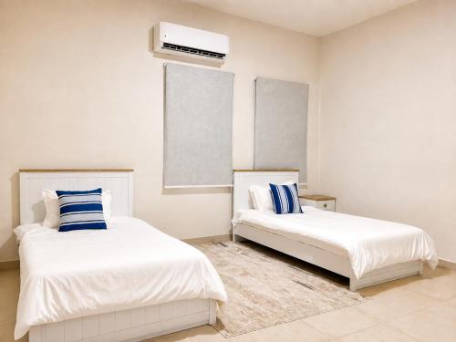 a bedroom with two beds and a air conditioner at Valley Farmhouse By Bait Zain in As Sīfah