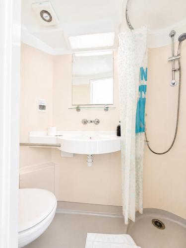 a white bathroom with a sink and a toilet at High Trees Guest House Gatwick in Horley