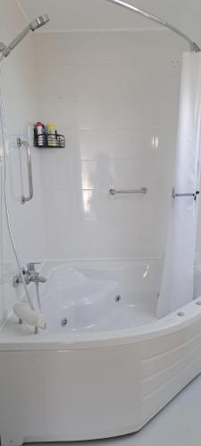a white bathroom with a tub and a sink at Apartman Romansa in Fojnica