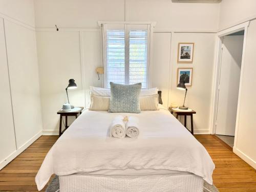 a bedroom with a large white bed with towels on it at Barbara's Byron Bay in Byron Bay
