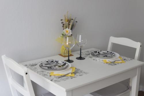 a white table with two plates and a wine glass at Dzīvoklis Baldone, Latvija in Baldone