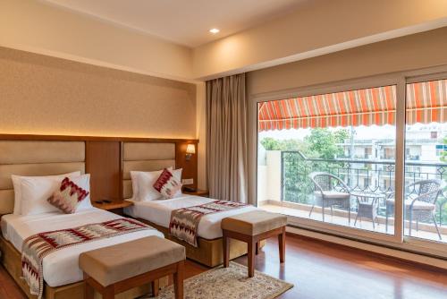 two beds in a hotel room with a balcony at Hotel Le Amritam in Dehradun
