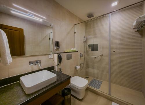 a bathroom with a sink and a toilet and a shower at Hotel Le Amritam in Dehradun