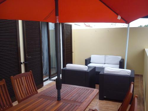 um guarda-chuva laranja sobre uma mesa com um sofá e cadeiras em Apartamento Sol e Mar 2 em Monte Gordo