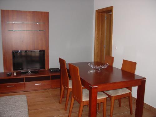 a dining room table with chairs and a television at Apartamento Sol e Mar 1 in Monte Gordo