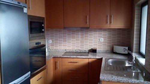 a kitchen with wooden cabinets and a sink at Apartamento Sol e Mar 1 in Monte Gordo