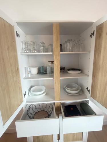 a cupboard with plates and dishes in it at Le Ptit Roc, cocon cosy in Chailles