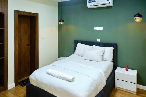 a bedroom with a white bed with a green wall at Revkon Apartments in Abuja