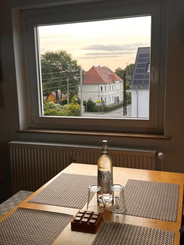 a bottle of wine sitting on a table with a window at Ferienwohnung mit Schminktisch 2OG in Gräfenhainichen