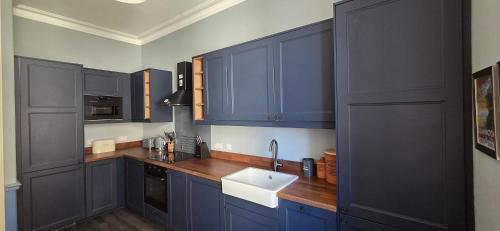 a kitchen with blue cabinets and a white sink at Bishop Street Apartment in Rothesay