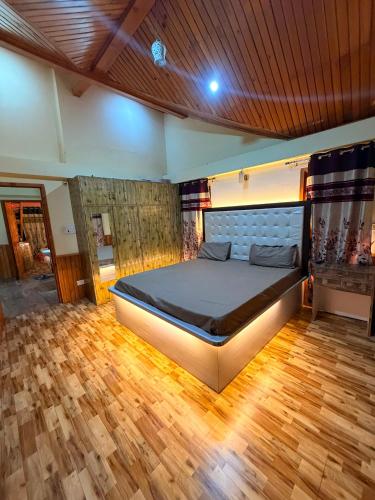 a bedroom with a large bed with a wooden floor at Himalayan Whisper in Kulu
