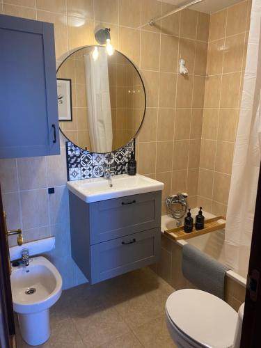 a bathroom with a sink and a toilet and a mirror at V&B VACACIONAL in Suances