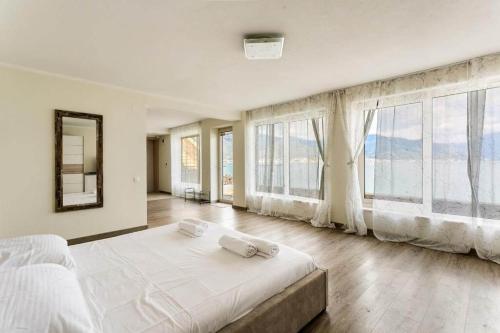 a white bedroom with large windows and a large bed at Marso in Krašići