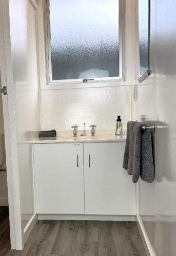 a white bathroom with a sink and a window at Charlton Motel in Gore