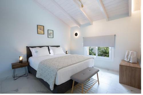 a white bedroom with a large bed and a window at Dante Home's in Corfu