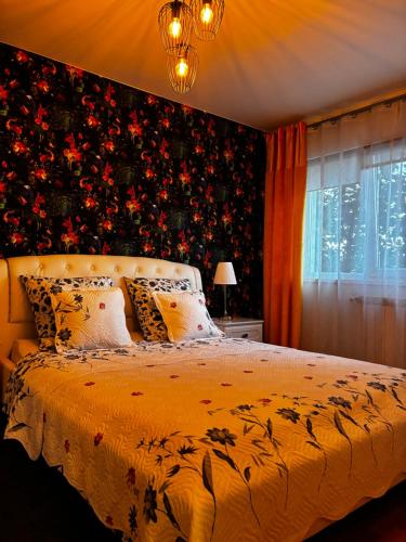 a bedroom with a bed with a floral wall at Apartament Lyonnet in Orşova