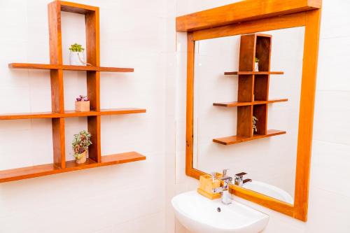 a bathroom with wooden shelves above a sink at Pericare Évasion Saly Espace exclusivement féminin in Saly Portudal