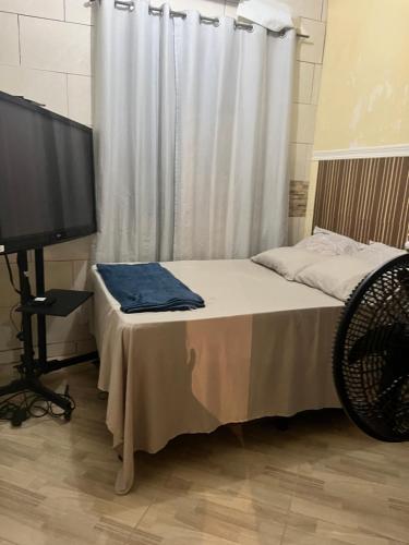 a bedroom with a bed with a television and a curtain at Casa em Marataízes - Espírito Santo in Marataizes