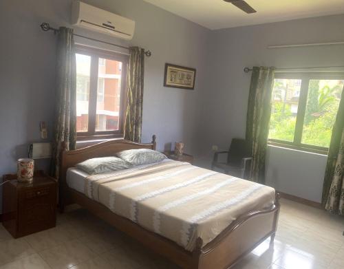a bedroom with a bed and a large window at Dona Paula Apartment in Dona Paula