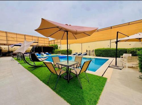a table and chairs with an umbrella next to a pool at Dahab Luxury Villa with Private Pool in Al Rama