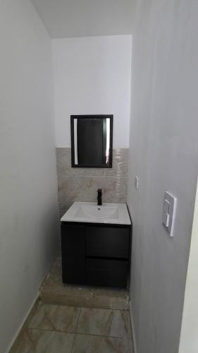 a bathroom with a sink and a tv on the wall at Bambú Alojamiento in Carmen de Apicalá