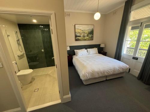 a bedroom with a bed and a bathroom with a shower at Tall Timbers Motel in Dungog