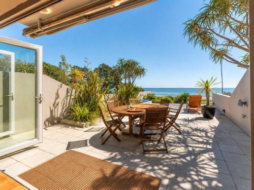 a patio with a table and chairs and the ocean at The Sands - Villa 28 - Stay Waiheke in Onetangi