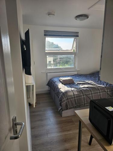 a small bedroom with a bed and a window at Modern Fully Contained En-Suite Room With Kitchen in Sidcup
