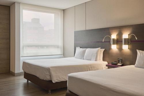 a hotel room with two beds and a window at Mercure Bogota BH Zona Financiera in Bogotá