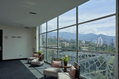 a room with chairs and a view of a bridge at Hotel bh El Poblado in Medellín