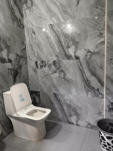 a bathroom with a toilet and a marble wall at HoTEL MADHAVI PRIME in Guntūr
