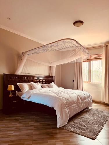a bedroom with a large bed with a canopy at Excutive suites in Kyebando